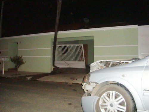 Carro bate em poste e danifica portão de residência